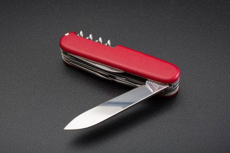 Red multitool open knife on black background