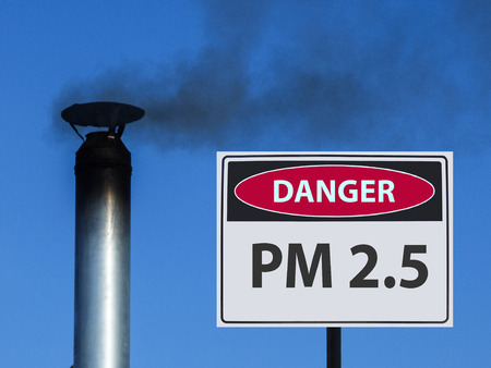 the sign of pm 2.5 and the house chimney with smoke against the sky.の写真素材
