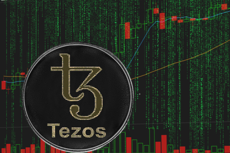 Coin Tezos XTZ cryptocurrency on the background of binary crypto matrix text and price chart.の写真素材