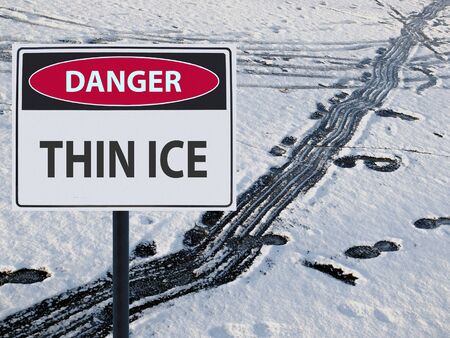 sign thin ice and footprints on snow and iceの写真素材