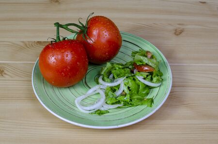 tomatoes from the garden with green leaf lettuce in composition on a wooden table backgroundの写真素材