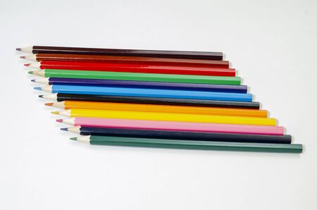 different colored pencils arranged in order on a white surfaceの写真素材