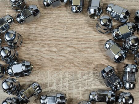 car wheel nuts isolated on table background, round frame made of wheel nuts. Close-up of various steel nutsの写真素材