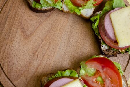 fresh sandwich with sausage and lettuce on a wooden standの写真素材