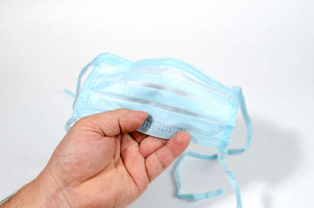 man holds a protective mask in his hand, worries about coronovirusの写真素材