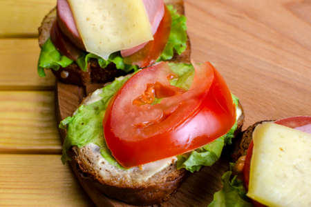 fresh sandwich with sausage and lettuce on a wooden standの写真素材