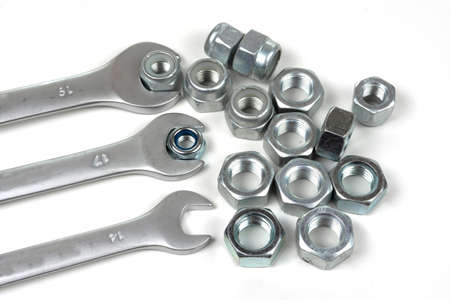 set of wrenches and several nuts on a white background