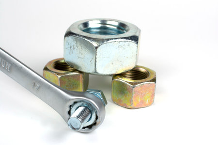 several metal nuts and bolts with a wrench on a white background