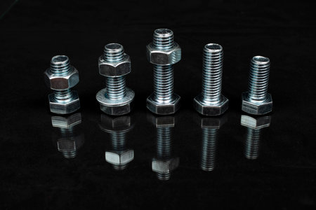 metal bolts and nuts group on black background