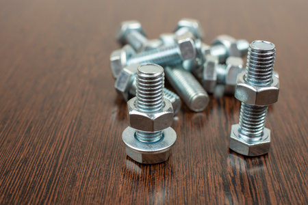bolts and nuts from a metal group on a wooden table
