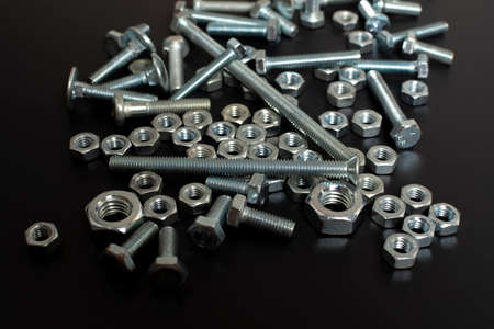 many metal bolts and nuts against black backgroundの写真素材