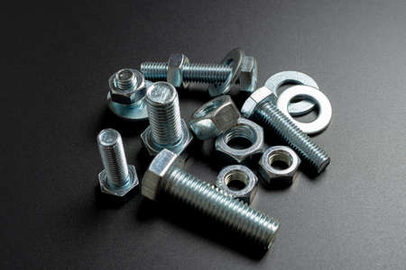 several metal bolts and nuts against black background