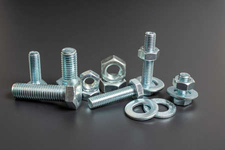 several metal bolts and nuts against black background