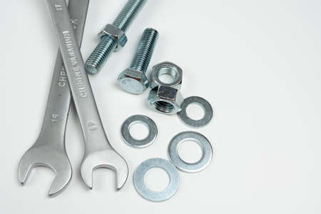 silver metal bolts and nuts and wrenches on white background