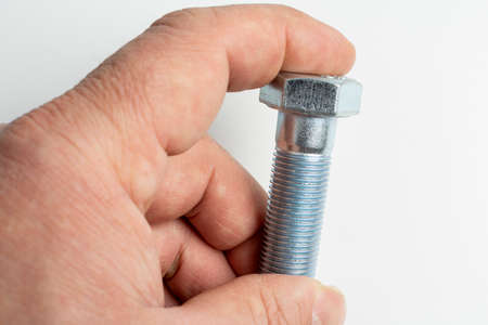 man holds large metal bolts in his hand
