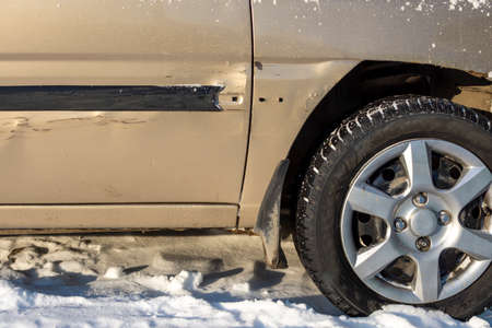 car in winter with minor damage to the wing and door