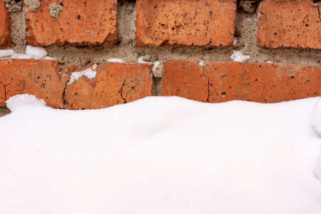 a small patch of snow near a red brick wallの写真素材