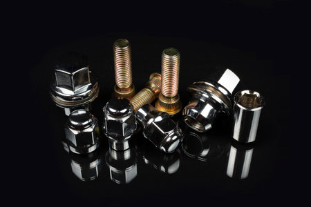 close-up on a black background studs and nuts for fastening the wheels of the car