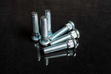 several studs fastening a car wheel on a black background