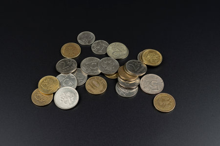 a scattering of metal coins on a black background close upの写真素材