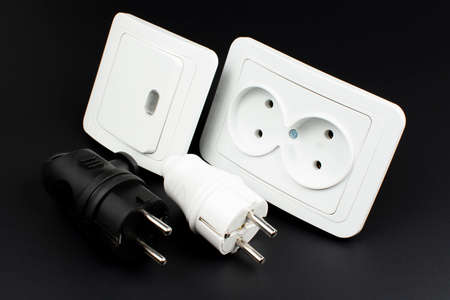 Close-up of electrical outlet, plugs and light switch on black