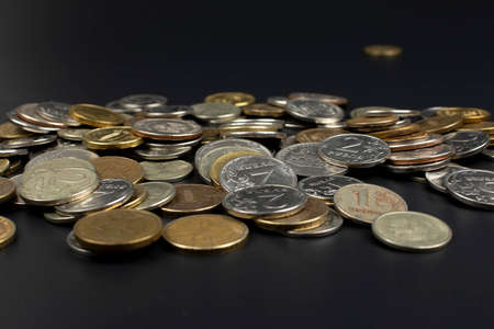 a scattering of metal coins on a black background close upの写真素材