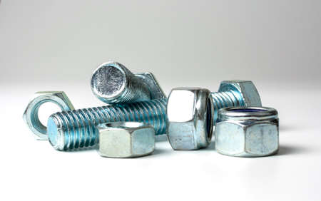 group of bolts and nuts made of light metal on a white background