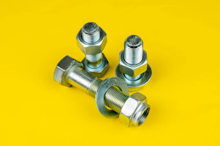metal bolts and nuts on yellow backgroundの写真素材