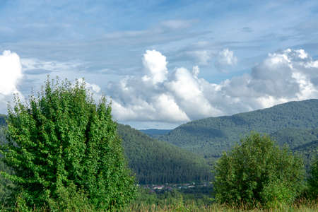white fluffy clouds on blue sky and mountain peaks