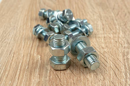 a few nuts and bolts on a wooden surfaceの写真素材