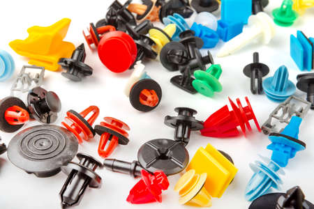 Close-up shot of plastic colored clips for the car.Abstract background. Panel plastic rivets isolated on white background. Auto plastic clasps. Insulated clip or automatic plastic claspの写真素材