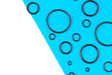 Black hydraulic and pneumatic o-rings in different sizes on a blue and white background. Rubber...