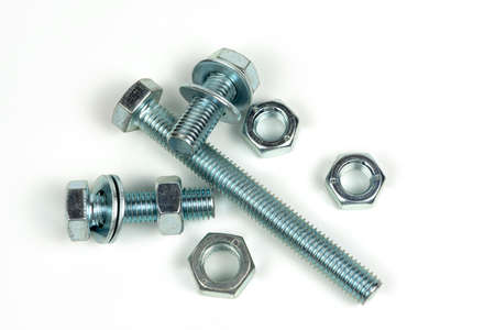 several metal washers, nuts and bolts of silver color on a white background. close up