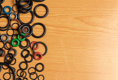Black hydraulic and pneumatic o-rings in different sizes on a wooden background. Sealing rings for hydraulic connections. Rubber seals for plumbing.の写真素材