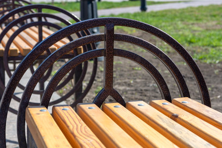 wooden benches in a city park with openwork metal armrestsの写真素材