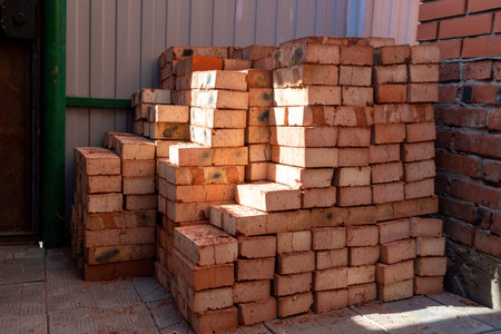 Red bricks stacked on a construction site close-up. Building stone prepared for construction