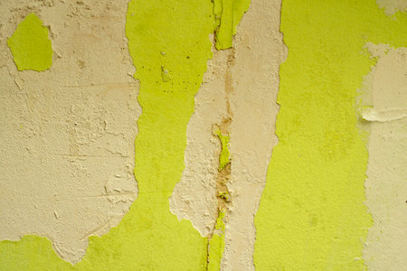 Green damaged plaster on concrete wall, old plaster needs repair. Abstract background, close-up, copy spaceの写真素材