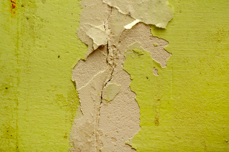 Green damaged plaster on concrete wall, old plaster needs repair. Abstract background, close-up, copy spaceの写真素材
