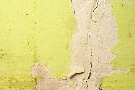 Green damaged plaster on concrete wall, old plaster needs repair. Abstract background, close-up, copy spaceの写真素材
