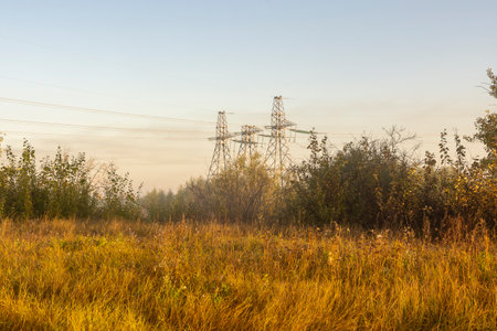 Picturesque view of landscape against sky in foggy weather. Power lines in the background. Warm...