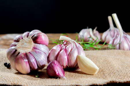 garlic bulbs and cloves arranged on an old board.の写真素材