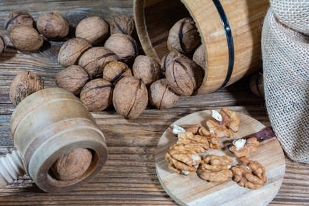 walnuts sprinkled from a wooden barrel onto an old board, peeled nuts on a wooden board.の写真素材