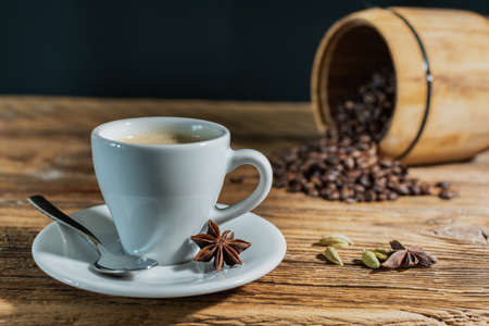 espresso cup with black roasted coffee beans in the background on an old wooden table top.の写真素材