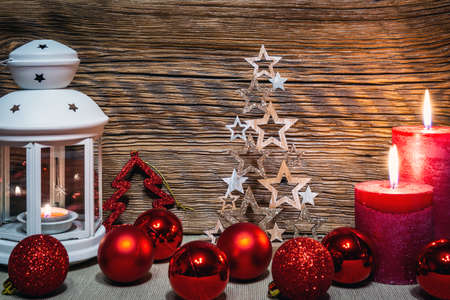 Christmas decoration. A festive lantern against an old wooden wall, surrounded by Christmas balls.の写真素材