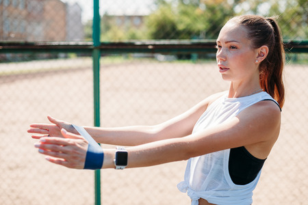 Young sporty woman doing exercises with rubber band outdoor