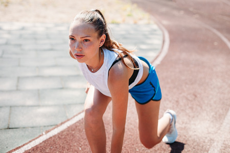 Young athletic woman preparing to run at the stadium, outdoors. The concept of a healthy lifestyle