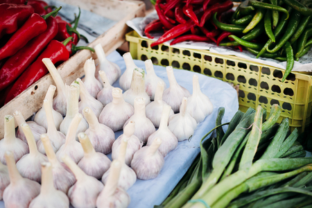 pile of garlic on the market on the background of red chili peppers and greenの写真素材