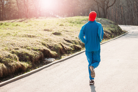 man athlete in sportswear summer early morning running in the Park. healthy lifestyle concept. rear...