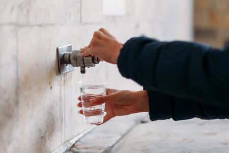 Yessentuki, Stavropol Territory / Russia - February 26, 2019: Drinking gallery of mineral spring Essentuki â 17. indoors. close - up of young woman gaining glass of mineral water from tapのeditorial素材