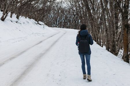 man walking in the snow road in forestの写真素材